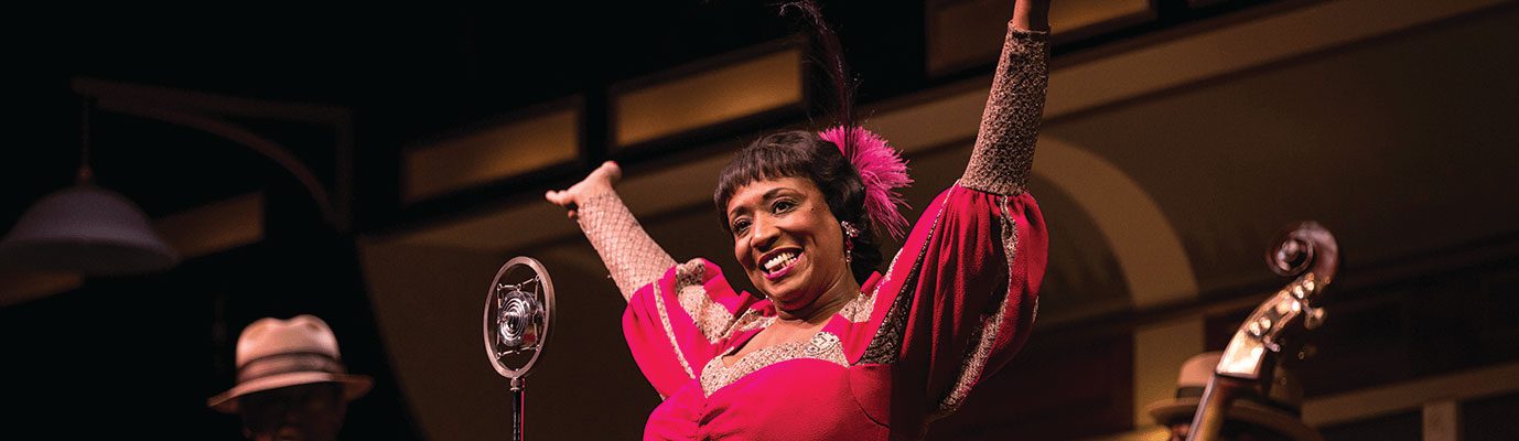 Woman standing in celebration on stage in front of mic