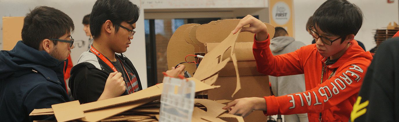 Three students using cardboard to build stage props.