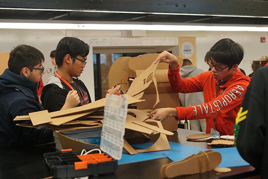 Three students using cardboard to build stage props.