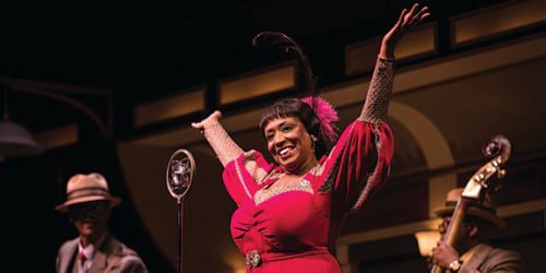 woman on stage with hands in air