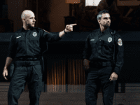 Two cops standing looking to their left, one is pointing a finger.