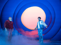 Two people looking surprised with a light orb and fog behind them,