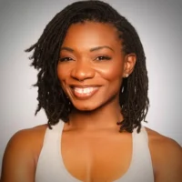 Woman with shoulder-length, twisted hair smiling and wearing a light-colored tank top against a plain, gradient background.