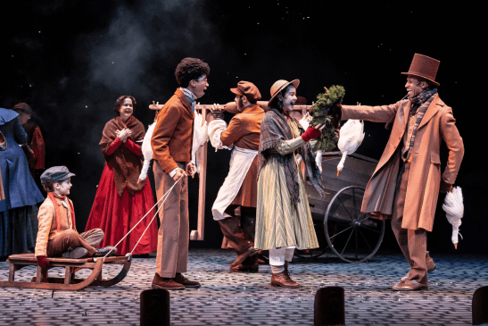 Actors in Dickens-era costumes buying a Christmas wreath