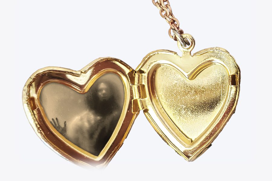 A shadowy figure appears on the left side of an open, heart-shaped locket on a chain, as if pressing against a steamy window.