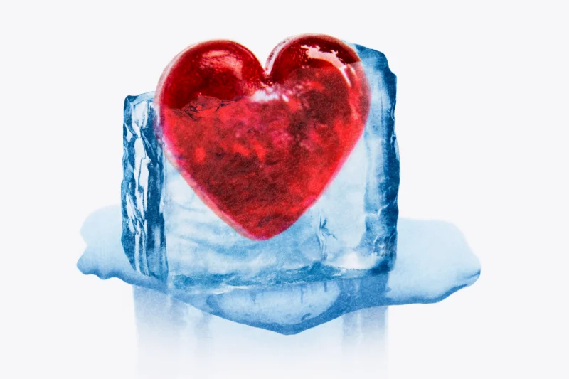 A red heart encased in a melting block of ice against a white background.