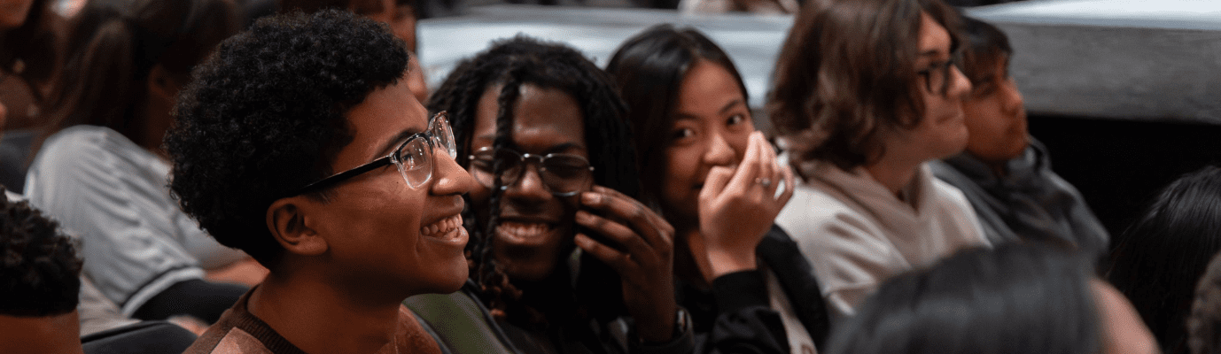 Several giggling students sitting in the audience for a performance.