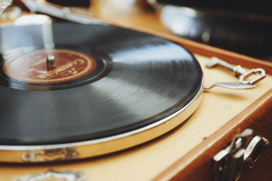 Wooden record player with a black vinyl playing.