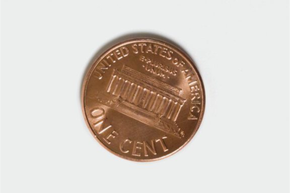 A U.S. one cent coin showing the Lincoln Memorial on the reverse side, with “United States of America” and “One Cent” inscribed.