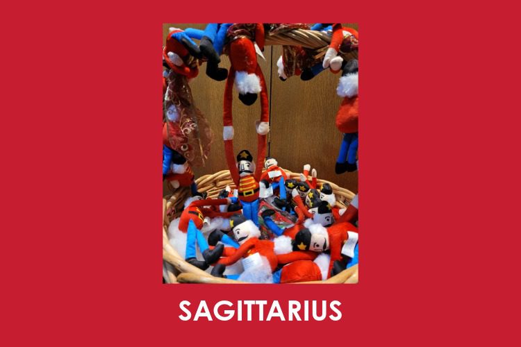 A wicker basket filled with small toy soldiers and Santa Claus dolls, with "SAGITTARIUS" written below on a red background.