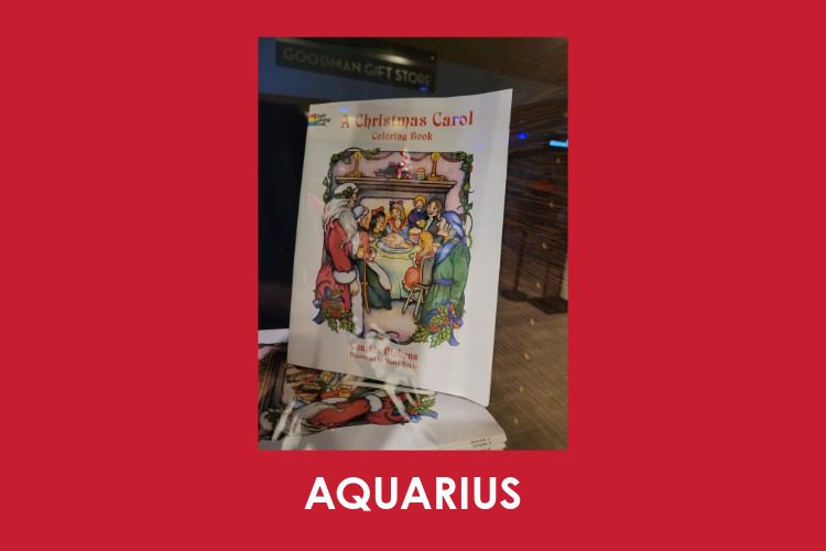 A coloring book titled "A Christmas Carol" is displayed in a store window; the word "AQUARIUS" appears below on a red background.