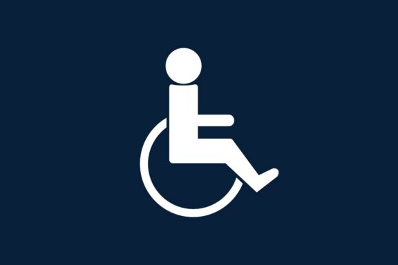 White wheelchair accessibility icon on a dark blue background, depicting a person seated in a wheelchair.