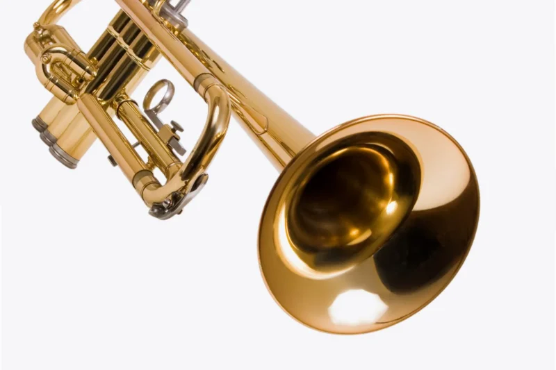 Close-up of a brass trumpet against a white background, showing the bell and valve section in detail.