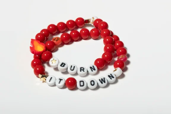 Two red beaded bracelets, one with a flame charm and the other with white beads spelling "BURN IT DOWN," are displayed on a white background.