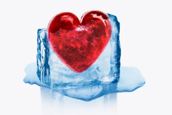 A red heart encased in a melting blue ice cube against a white background.