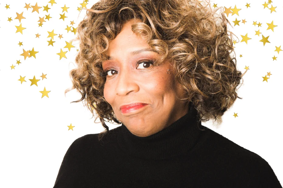 A middle-aged Black woman with curly hair wearing a black turtleneck sweater, framed by gold star graphics on a white background.