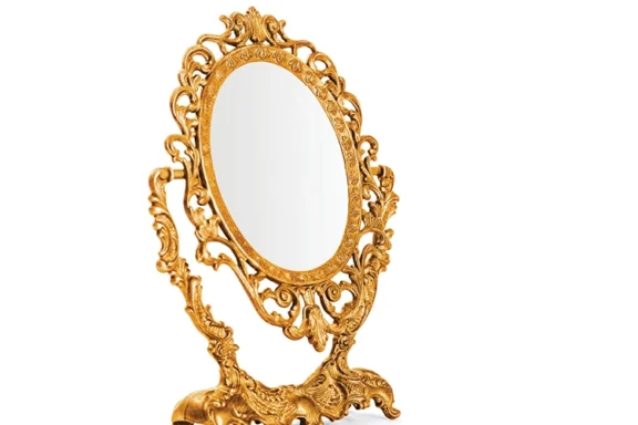 Oval tabletop mirror with an ornate, gilded scrollwork frame.