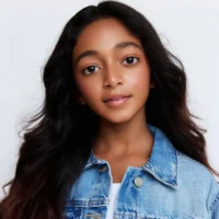 A young girl with long dark hair wearing a denim jacket.